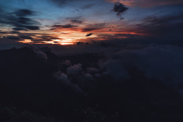 Fototapeta na wymiar Dark photo of sunrise in mountains with clouds and sun rays on Java