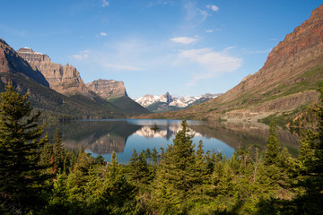 Early morning in the Glacier National Park with a serene lake surrounded by towering mountain peaks