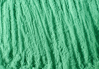 Green cosmetic clay powder (alginate facial mask, spirulina body wrap) texture close up, selective focus. Abstract background.