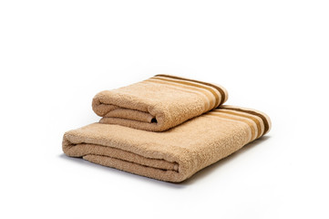 Stack of clean soft light brown towels on a white background, set for the bathroom, hygiene