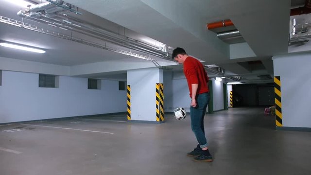 A man is stuffing a soccer mach in the garage. Active lifestyle in self-isolation. Physical education in an active game.
