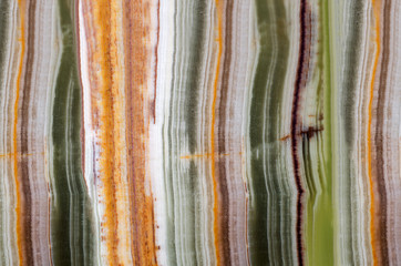 Onyx gemstone texture close up. Green, white, brown and orange stripes. Natural stone mineral background.