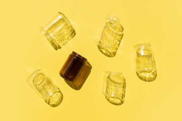 empty glass bottles with shadows pattern on yellow background
