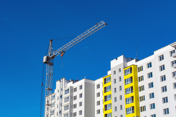 Crane and building construction site against blue sky