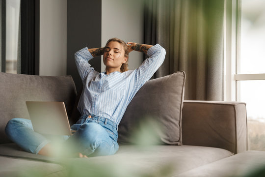 Image of young relaxed woman resting while sitting with laptop