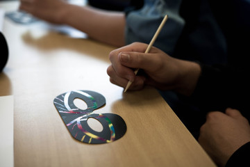 Hands of a child making an animal mask on a desk.  Crafting and having fun making things.