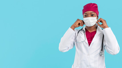 Fototapeta na wymiar Female black doctor adjusting her surgeon mask