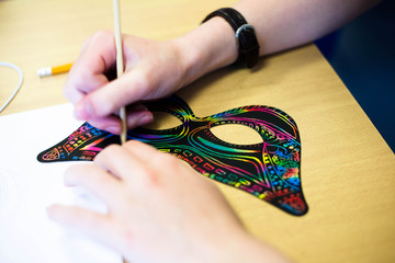Masks on a desk having a design scratched onto it.