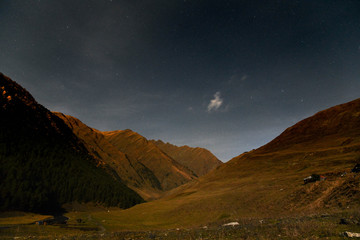 Fototapeta na wymiar The Tusheti Mountains at night under a starry sky with a moving cloud