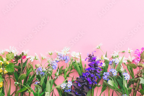 Wildflowers colorful border on pink paper background, flat lay with space for text. Blooming spring flowers, floral greeting card template. Happy Mother's day concept. Hello spring