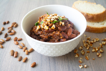 Traditional Georgian vegan kidney beam stew lobio with chopped walnuts and parsley served in a bowl with slices of bread