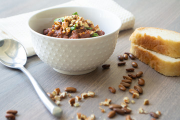 Traditional Georgian vegan kidney beam stew lobio with chopped walnuts and parsley served in a bowl with slices of bread