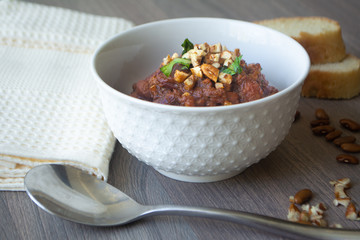 Traditional Georgian vegan kidney beam stew lobio with chopped walnuts and parsley served in a bowl with slices of bread