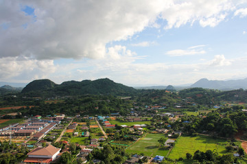 Fototapeta na wymiar View of a small village, vegetation and green mountains from above the Big Buddha of Chiang Rai