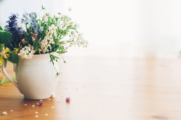 Wildflowers bouquet in old cup on wooden table,  space for text. Blooming spring flowers in soft light, rural still life. Happy  Mother's day. Hello spring.