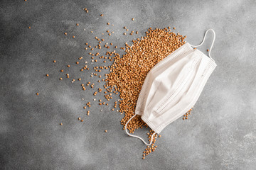 The texture of dry buckwheat and medical mask on grey background