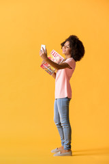 African-American teenage fashion blogger with mobile phone on color background