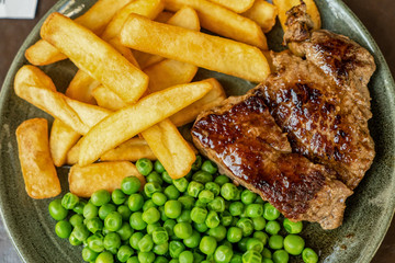 Steak with green peas and fries.