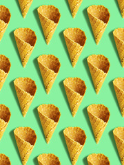 Pattern with empty waffle cones on mint color background.