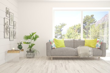 Fototapeta premium White living room with sofa and summer landscape in window. Scandinavian interior design. 3D illustration