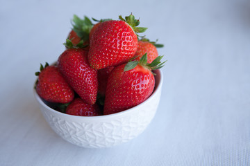 Strawberries in the ceramic bowl on the table. Natural day light.