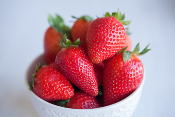 Strawberries in the ceramic bowl on the table. Natural day light.