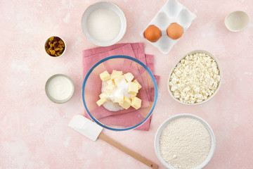 Fototapeta na wymiar flour, cottage cheese in bowl and milk, eggs. products for making cheesecakes on a pink backround.