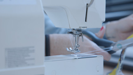 Female sewing together face mask with a sewing machine