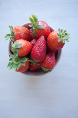 Strawberries in the ceramic bowl on the table. Natural day light. Top view