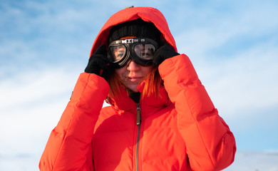 
beautiful redhead woman in snowboard glasses and a red jacket travels around Iceland in winter