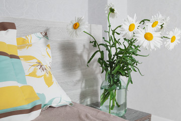 Daisies in vase on bedside table