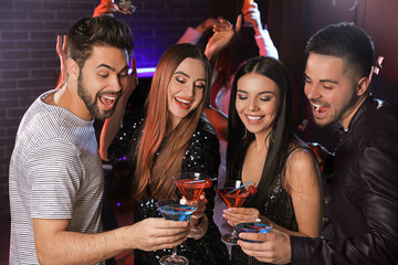 Happy young people with cocktails in night club