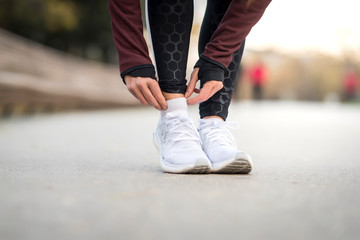 Close up detail of unknown female runner hands on her foots