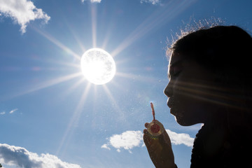 girl blowing bubbles with the sun closed in a bubble
