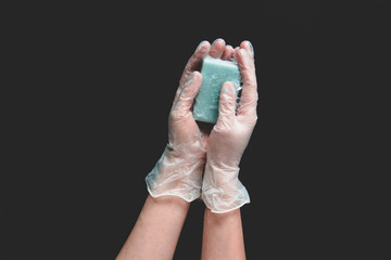 Wash hand. Woman's hands with transparent protective gloves holding soap on a black background. Soap, protect, glove. Coronavirus, COVID-19.