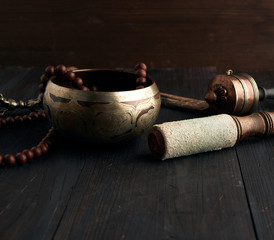 Tibetan singing copper bowl with a wooden clapper on a brown wooden table, objects for meditation...