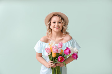 Beautiful young woman with bouquet of flowers on color background