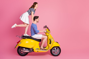 Fototapeta na wymiar Profile side view portrait of his he her she nice attractive cheerful cheery funky carefree couple riding moped girl standing fooling having fun weekend isolated on pink pastel color background