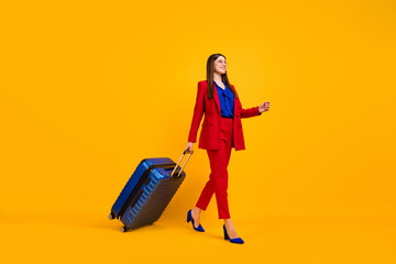 Full size profile photo of attractive business lady walk airport flight registration rolling suitcase wear specs red luxury blazer blouse pants suit shoes isolated yellow color background