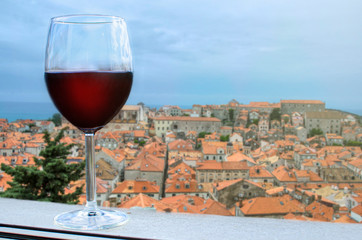 Glass of red wine with the view on reed rooftops of historic old Mediterranean tower in Croatia