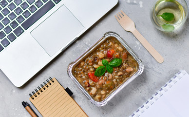 Food delivery. lunch box with a diet lunch or dinner on grey office table. Stewed beans with vegetables, takeaway lunch at the office. Top view. takeout healthy lunch. selective focus