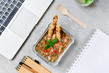 Food delivery. lunch box with a diet lunch or dinner on grey office table. Stewed beans with...