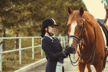 Obraz premium horsewoman jockey in uniform standing with black horse outdoors