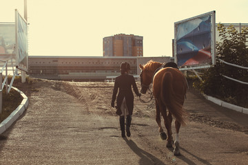 Rider woman with the horse are walking in a stable outdoors for dressage training
