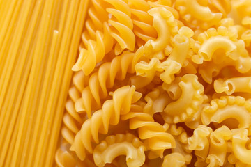Variety of types and shapes of dry Italian pasta as background