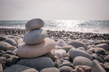 Fototapeta na wymiar Focused balanced cairns on beach in front of the sea