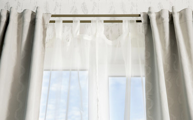 Double curtain rods for see through day curtain and room darkening night curtains. Hanging in front of a window with blue sky.