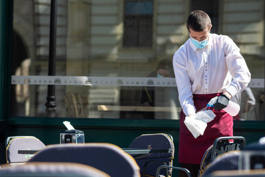 Waiter with a mask disinfects the table of an outdoor bar, café or restaurant, reopen after quarantine restrictions 