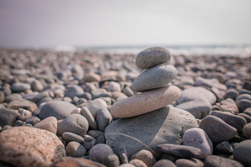 Fototapeta na wymiar Focused balanced cairns on beach in front of the sea