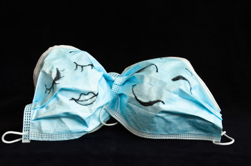 Two funny protection masks against Corona, with faces, like a man and a woman, are flirting...